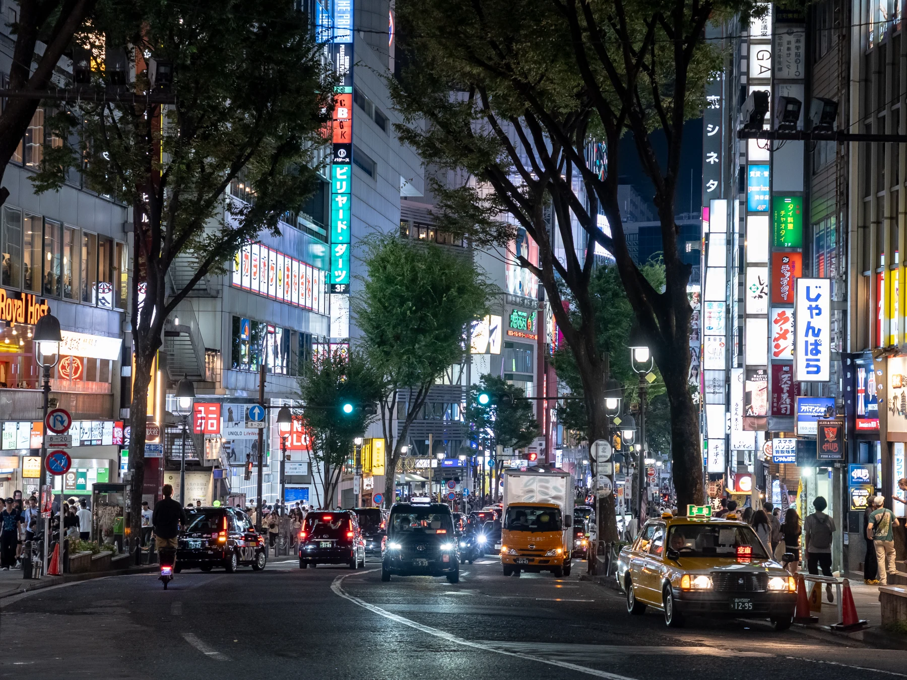ネオンと街路樹が連なる夜の道玄坂
