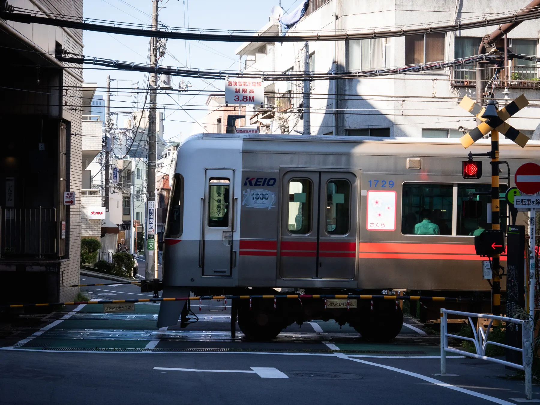 昼の神泉駅そばの踏切を通過する京王井の頭線